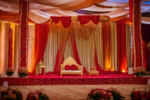 an indian wedding stage decorated with red and gold. AI-Generated photo