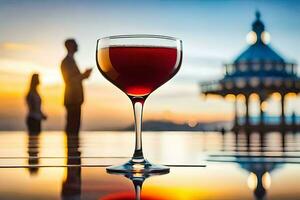 un vaso de rojo vino en un mesa en frente de un puesta de sol. generado por ai foto