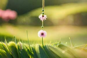 a pink flower hanging from a string in the grass. AI-Generated photo