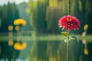 a red flower is hanging from a chain by a lake. AI-Generated photo