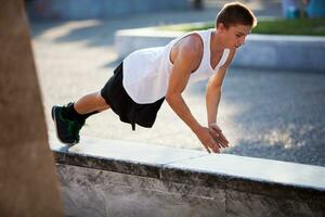 Teenager performing push-ups outdoor in city photo