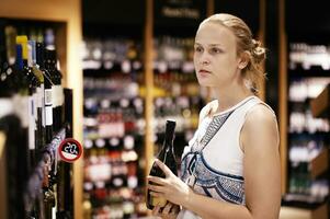 mujer compras para alcohol en un botella Tienda foto