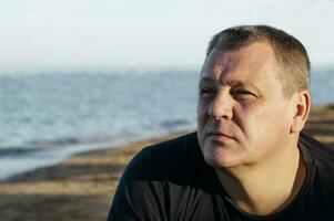 Handsome middle-aged man thinking at the beach photo