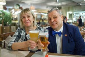 A portrait of a smiling middle aged couple with glasses of beer photo