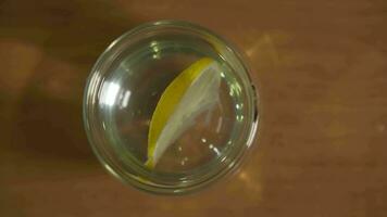 Top view of a glass of clean water with a lemon floating inside. video