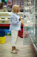 mujer elegir productos en abierto refrigerador con lechería foto