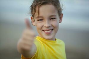 Outdoor portrait of a happy boy with thumbs-up photo