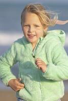 A 5-year-old girl in a green jacket is running photo