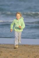 el niña es corriendo a lo largo el playa por el mar foto