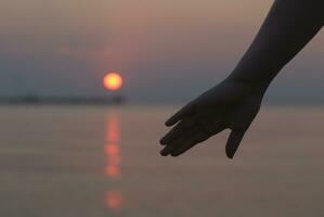 Womans hand silhouetted against a sunset photo