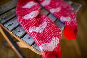 Red socks with heart pattern on wooden chair photo