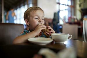 Little boy having sandwich in a cafe photo