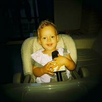 A little girl is sitting with a microphone photo