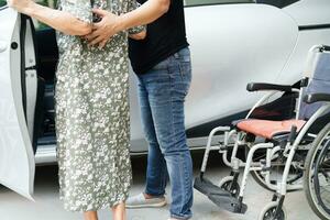 Caregiver help Asian elderly woman disability patient get in her car, medical concept. photo