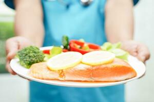 Asian Nutritionist holding healthy food for patient in hospital, nutrition and vitamin. photo