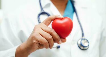 Asian woman doctor holding red heart for health in hospital. photo