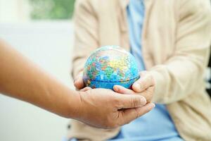 Bangkok, Thailand April 1, 2023 Asian elderly woman patient holding globe in hand at hospital. photo