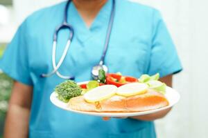 Asian Nutritionist holding healthy food for patient in hospital, nutrition and vitamin. photo