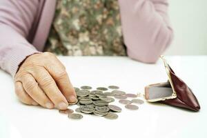 Retired elderly woman counting coins money and worry about monthly expenses and treatment fee payment. photo