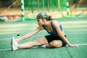 Sporty young woman in sportswear doing stretching exercises outdoors. Portrait of a young girl doing sport in the park. photo