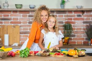 Happy mother and daughter are having fun in the kitchen. Healthy food concept. photo