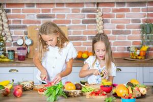 Two little girls in the kitchen with fresh vegetables. Healthy food concept. Happy sisters. photo