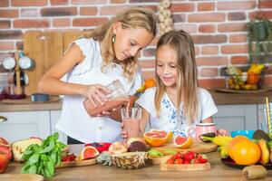 Two little girls in the kitchen with fresh vegetables. Healthy food concept.. Happy sisters photo