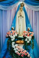 estatua de el Virgen María y el corona en el antecedentes de un azul cortina foto