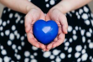 azul corazón en el manos de un mujer en un polca punto vestir foto