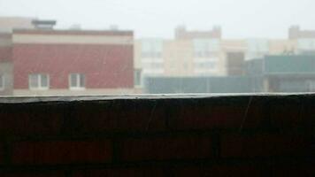 Raindrops dripping on the balcony railing. Roofs of houses in a residential area in the background. video