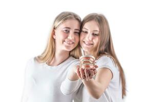 Two cheerful teenagers show in front of them a model of teeth with a braces photo