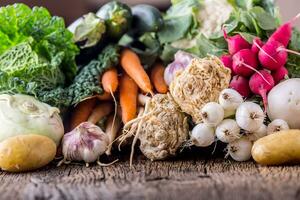 Assortment of fresh vegetables. Carrot garlic kohlrabi onion celery cucumber parsnip and radish on table. photo