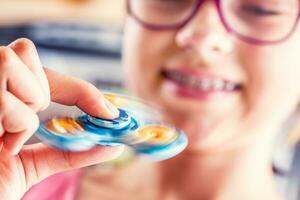 Fidget Spinner. Cute young girl playing with fidget spinner. photo