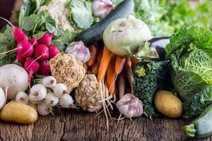 Assortment of fresh vegetables. Carrot garlic kohlrabi onion celery cucumber parsnip and radish on table. photo