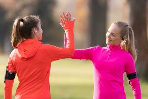 Two female athlete friends support each other and give high-five after a run photo