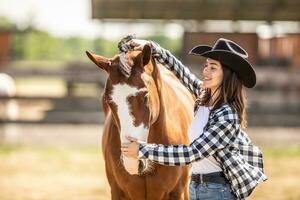 Young woman brushes her paint horse outdoors on a farm photo
