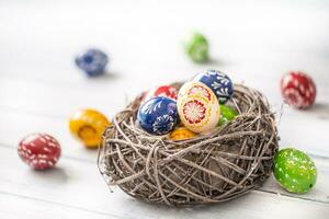 Close-up multicolored easter eggs in basket on wooden table photo