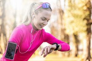 Young woman runner checks her smart watch after running in the park photo
