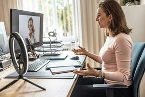 Screen view of a woman providing online customer service for an employee's office. A businesswoman gives an online interview with her client photo