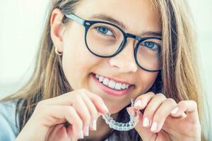 Dental invisible braces or silicone trainer in the hands of a young smiling girl. photo