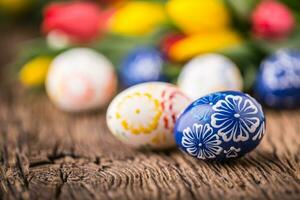 Easter. Hand made easter eggs and spring tulips on old wooden table. photo