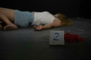 Female victim of violent crime lies on floor in abandoned room with evidence of red rope photo