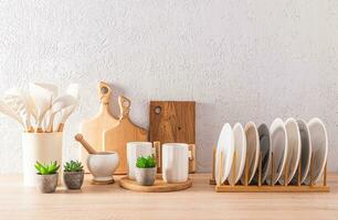 Various stylish white ceramic tableware on wooden kitchen countertop. A set of wooden cutting boards. Eco items in the kitchen. front view. photo