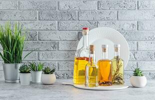 Various glass oil bottles for cooking on the kitchen countertop. Compact oil storage. Indoor flowers in pots. front view. photo