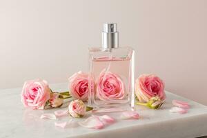 A chic bottle of women's perfume with a delicate rose aroma stands on a marble white podium. front view. small roses. Presentation of the fragrance. photo