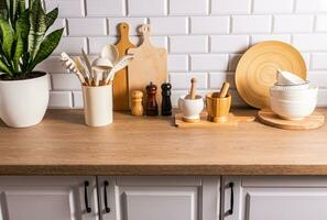 A set of various kitchen tools, utensils made of environmentally friendly materials on the kitchen countertop, a white brick wall. Eco-interior. photo