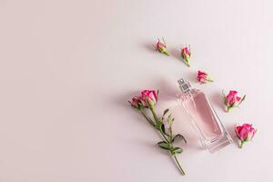 A beautiful bottle of women's perfume with a delicate aroma of roses on a pastel background among rosebuds. Top view. Flat lay. A copy space. photo