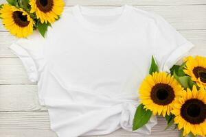 White womens cotton T Shirt mockup with sunflowers on white wooden background. Design t shirt template, print presentation mock up. Top view flat lay. photo