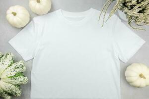 White womens cotton t-shirt mockup with pumpkins on gray concrete background. Design t shirt template, print presentation mock up. Top view flat lay. photo