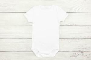 White baby girl or boy bodysuit mockup flat lay on wooden background. Design onesie template, print presentation mock up. Top view. photo